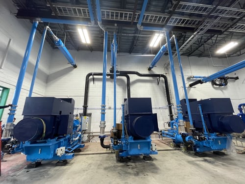 large blue industrial centrifugal air compressors system with piping in facility operations room 