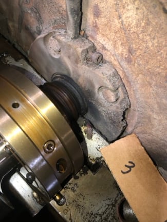 Close-up of a heavily rusted and deteriorated centrifugal compressor inlet and bearing assembly during initial teardown, marked with a cardboard tag labeled '3'.