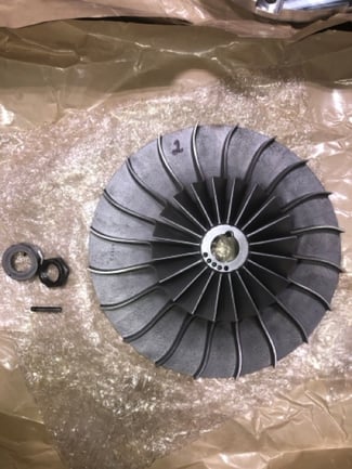 A clean, repaired centrifugal compressor impeller marked with a '2', resting on protective bubble wrap alongside its retaining nut and hardware.